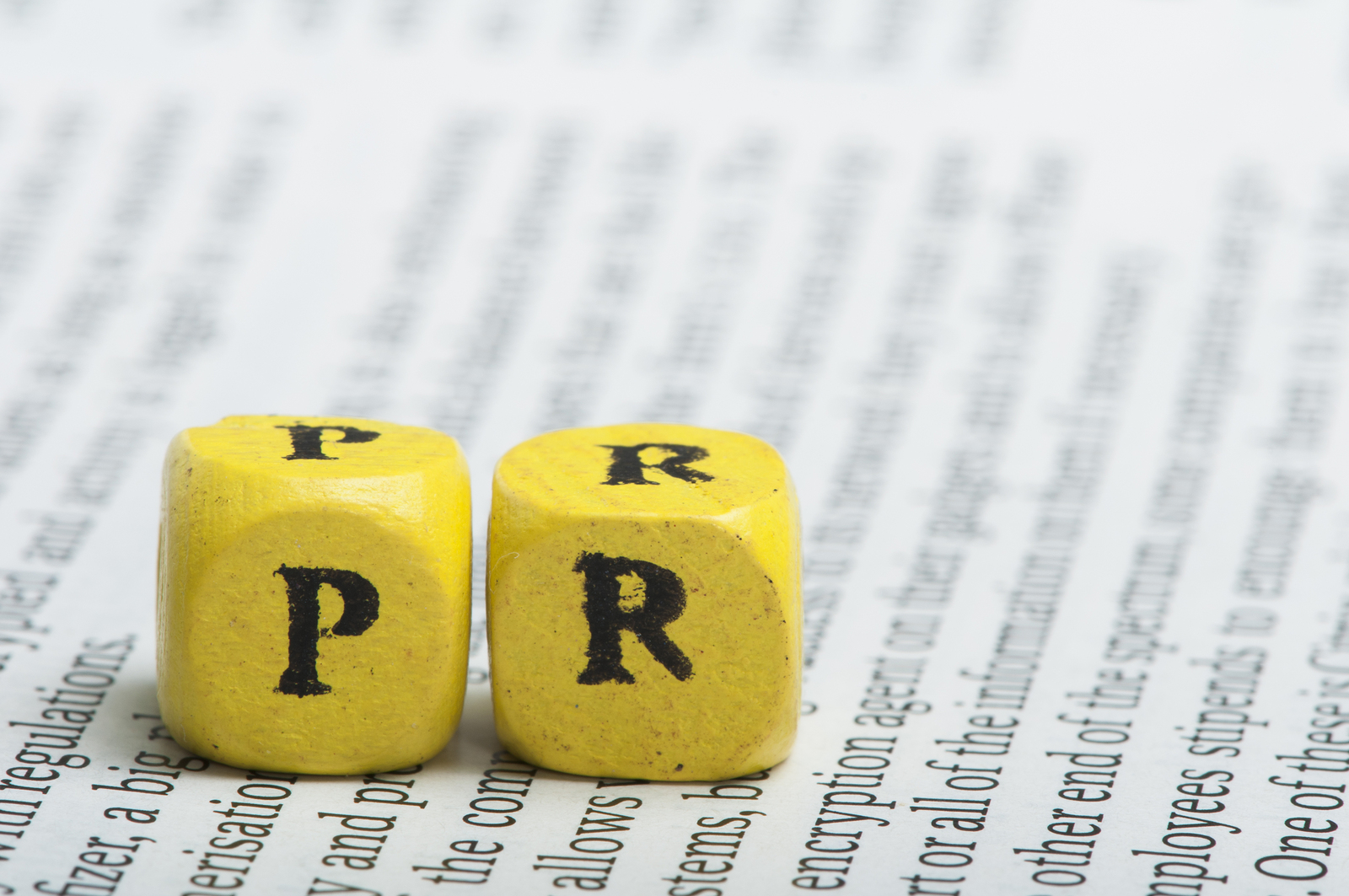 Word PR.Wooden cubes on newspaper. Close up studio shot